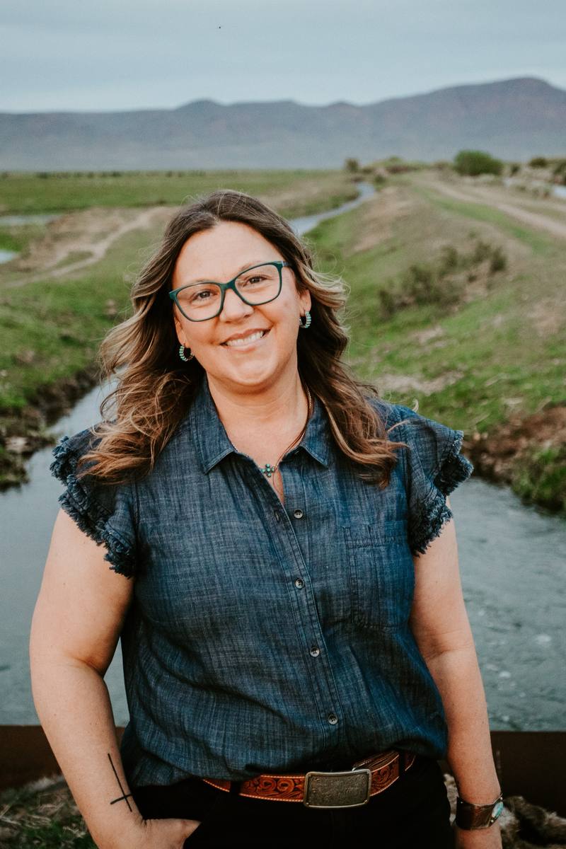 Rachel standing on a bridge with green fields and mountains